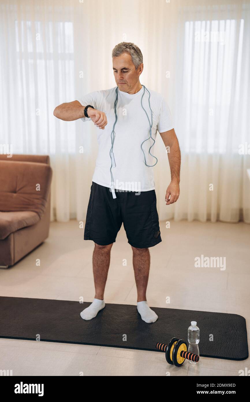 Fit man monitors his heart rate with a smart watch. Workout at home