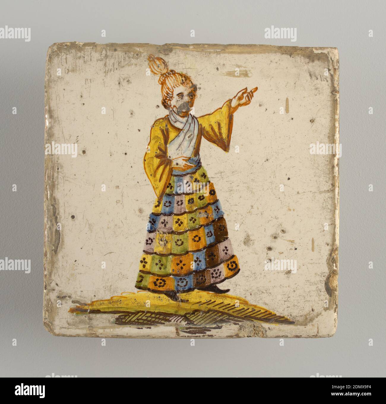 Tile, Earthenware, glazed and high fire decorated, Standing man, left arm raised and pointing to upper corner; dressed in multi-colored checkered skirt, yellow shirt and white shawl. Chinoiserie type of decoration., Alcora, Spain, late 18th–early 19th century, tiles, Decorative Arts, Tile Stock Photo