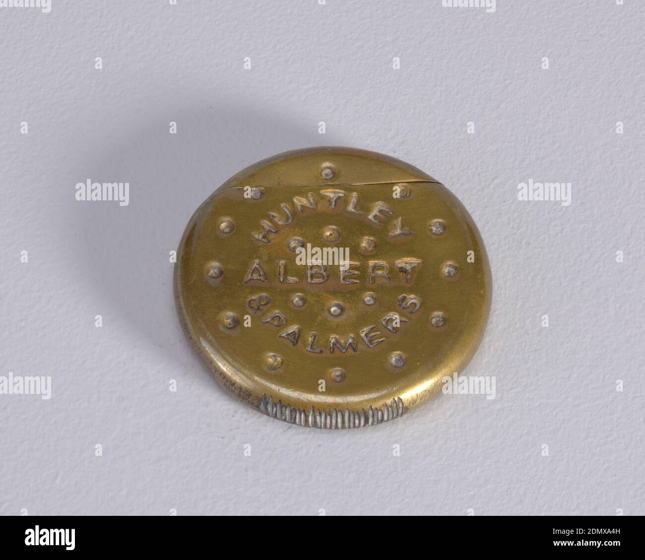 Huntley & Palmers 'Albert' Biscuit, Brass, Circular, in the form of a biscuit, with small, dot-like, simulated perforations on front surface, inscribed 'Huntley & Palmers,' 'Albert.' On reverse are small, vertical and horizontal, dash-like, simulated perforations. Outer circumference of box displays irregular, scratch-like marks in surface. Lid, or upper portion of biscuit, hinged on back. Striker on bottom edge., ca. 1890, containers, Decorative Arts, Matchsafe, Matchsafe Stock Photo
