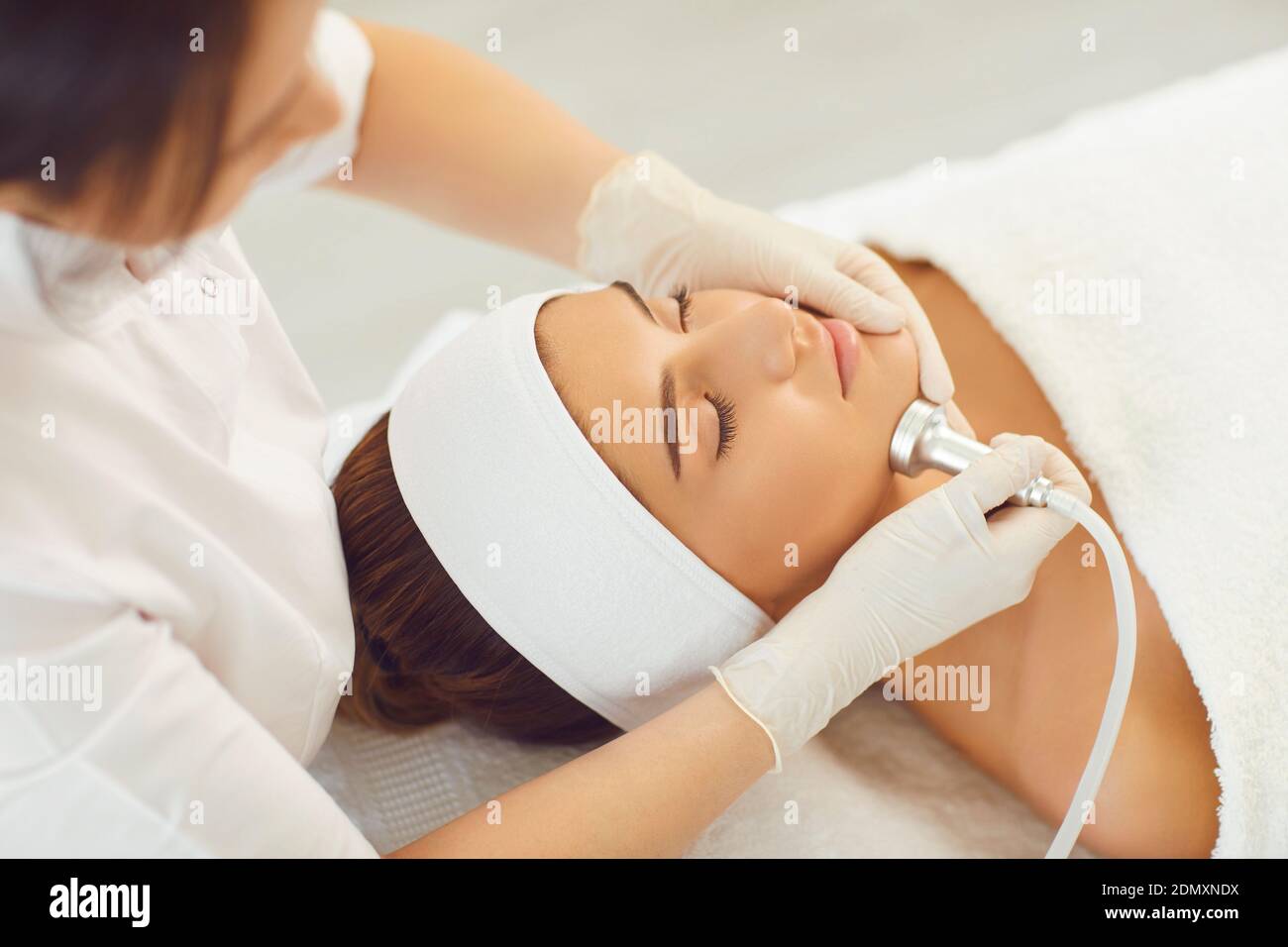 Cosmetologist making procedure of microdermabrasion of facial skin for woman Stock Photo