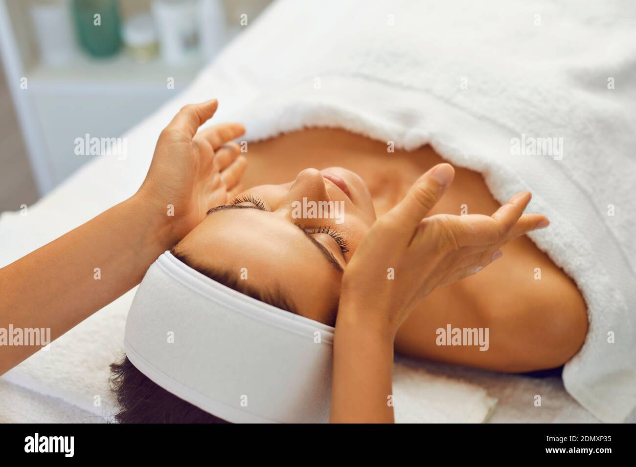 Young beautiful woman has relaxed and is enjoying a facial massage from a spa specialist. Stock Photo