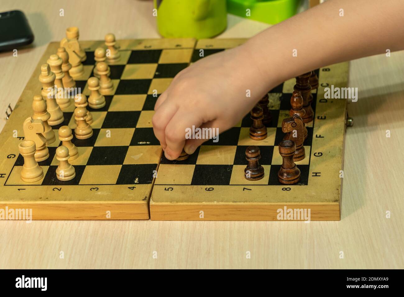 The child's hand holds a chess piece on a chessboard. Photo taken in Chelyabinsk, Russia. Stock Photo