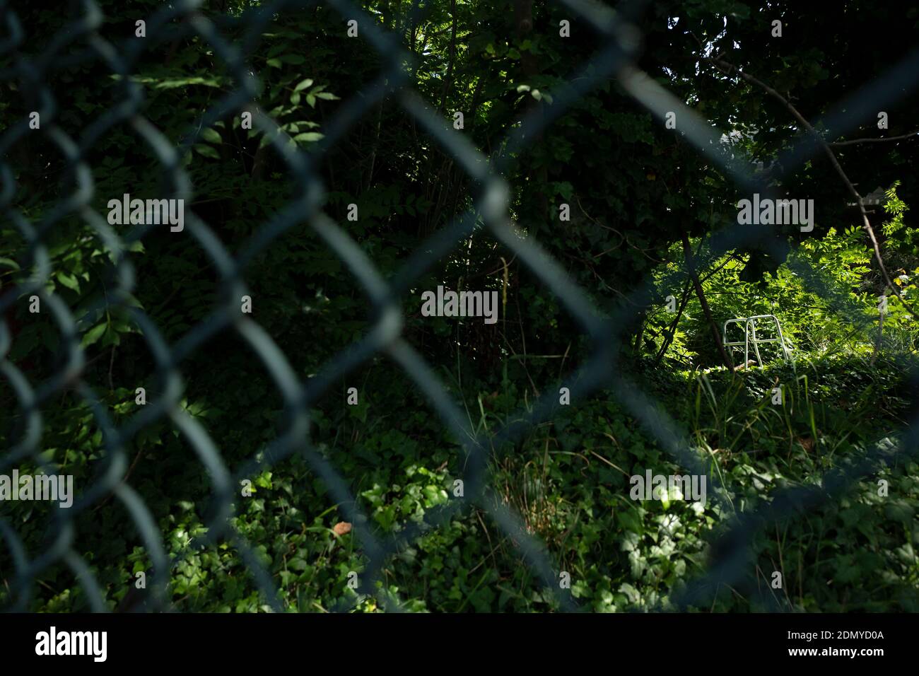 A zimmer frame is seen through a wire fence Stock Photo