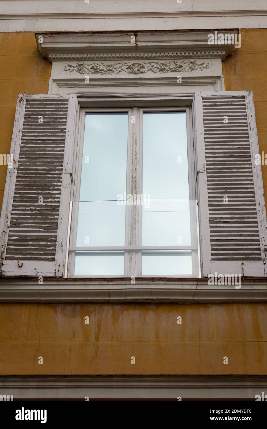 Mirror window with white shutters open in Madrid residential building