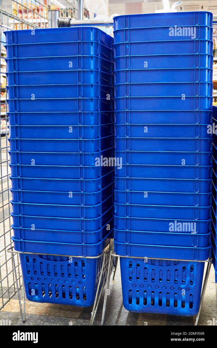 Stacks of blue plastic shopping baskets in a supermarket Stock Photo Alamy