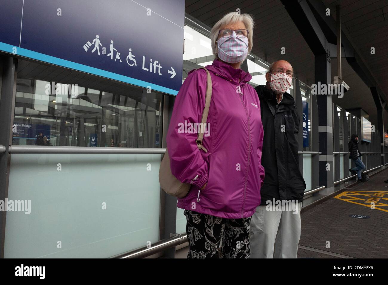 An elderly couple wear face masks as they wait at London Bridge station during the Coronavirus pandemic Stock Photo