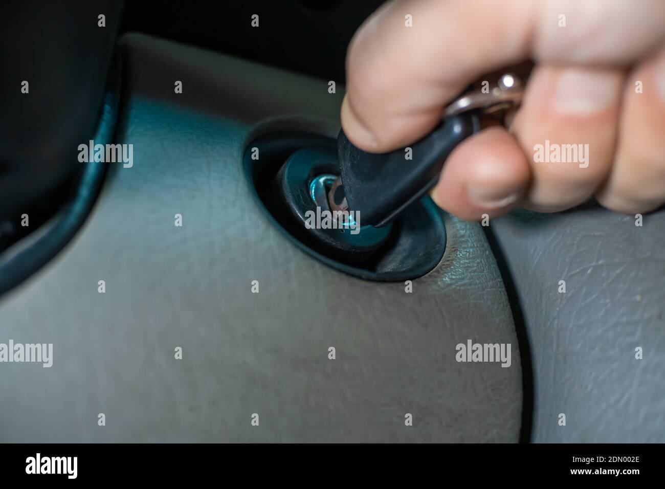 Man starts the car by turning the ignition key under the steering wheel