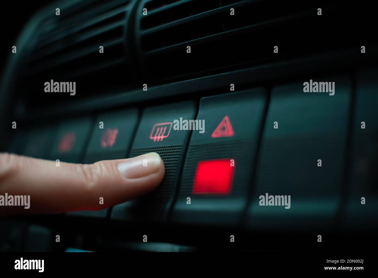 Woman's finger presses the emergency button highlighted in red on the instrument panel close up Stock Photo