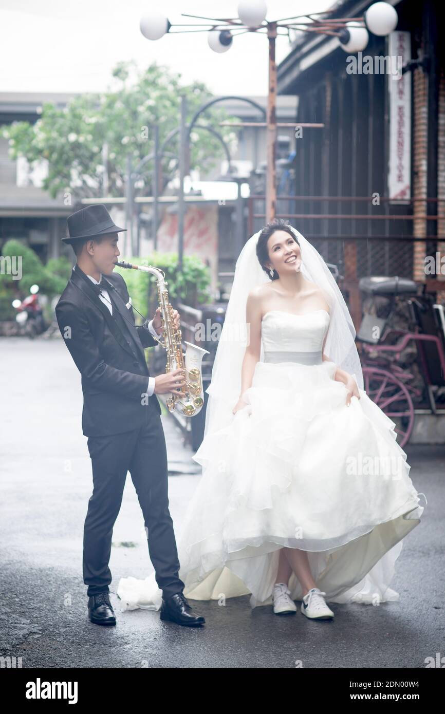 Full Length Of Man Playing Saxophone While Bride Walking On Road Stock  Photo - Alamy