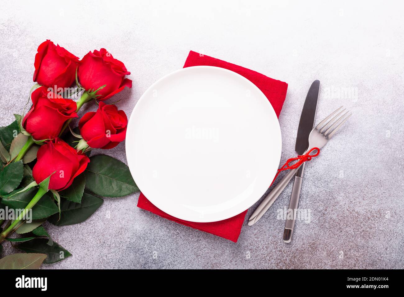 Valentines day table place setting with bouquet of red roses and ...