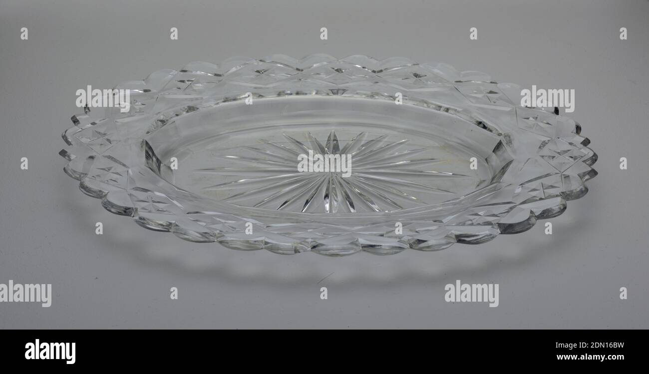Dish, Glass, Oval dish with wide rim scalloped at the edge, star cut at center, cavetto with facets, rim cut with flat diamond pattern, glass clear and heavy., possibly Cork, Ireland, ca. 1790, glasswares, Decorative Arts, Dish Stock Photo