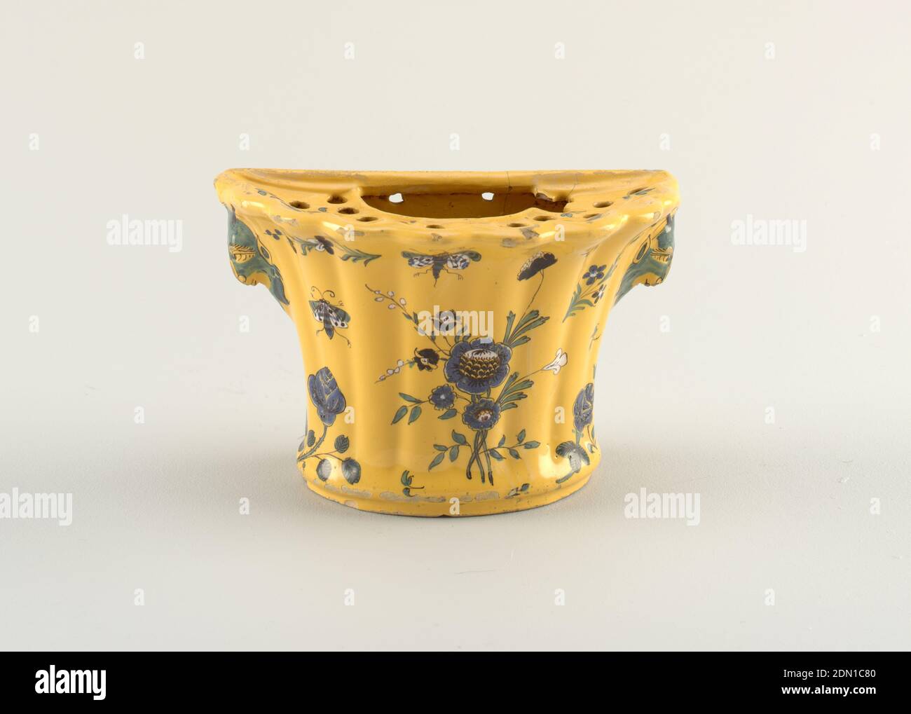 Bough pot, Molded and glazed earthenware with polychrome enamel, Flat at back, the bowed front ribbed and flaring, with two animal-head handles. Sunken top pierced with one large and many small openings. Scalloped rim. Decorated with flowers and insects in blue, green and white outlined in black, on a thick yellow ground., possibly Marseille, France, ca. 1750, ceramics, Decorative Arts, Bough pot Stock Photo