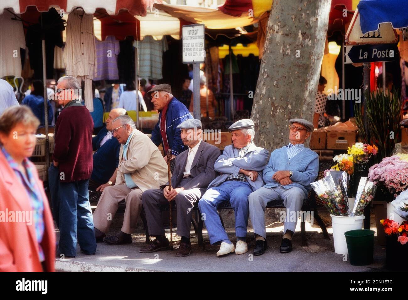 A group of old men sitting on a bench in the market square at Limoux. Occitanie, Aude, Languedoc Roussillon. France Stock Photo