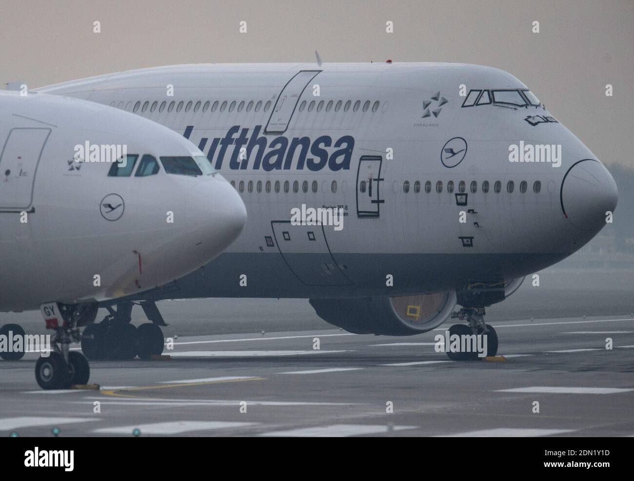 17 December 2020, Hessen, Frankfurt/Main: Temporarily idle Lufthansa passenger planes - including a Boeing 747-8 - stand in dense fog on the northwest runway of Frankfurt Airport. For the second time this year, the runway is being used as a parking lot due to the corona-related lull in the aviation industry. Photo: Boris Roessler/dpa Stock Photo