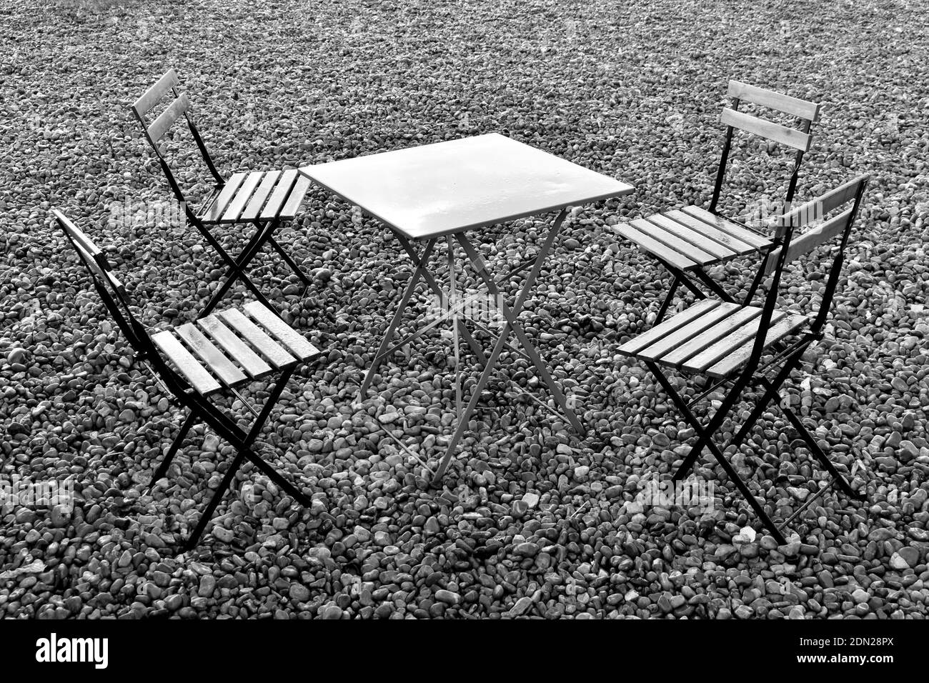 Empty table and chairs on the beach after the rain in black and white Stock Photo