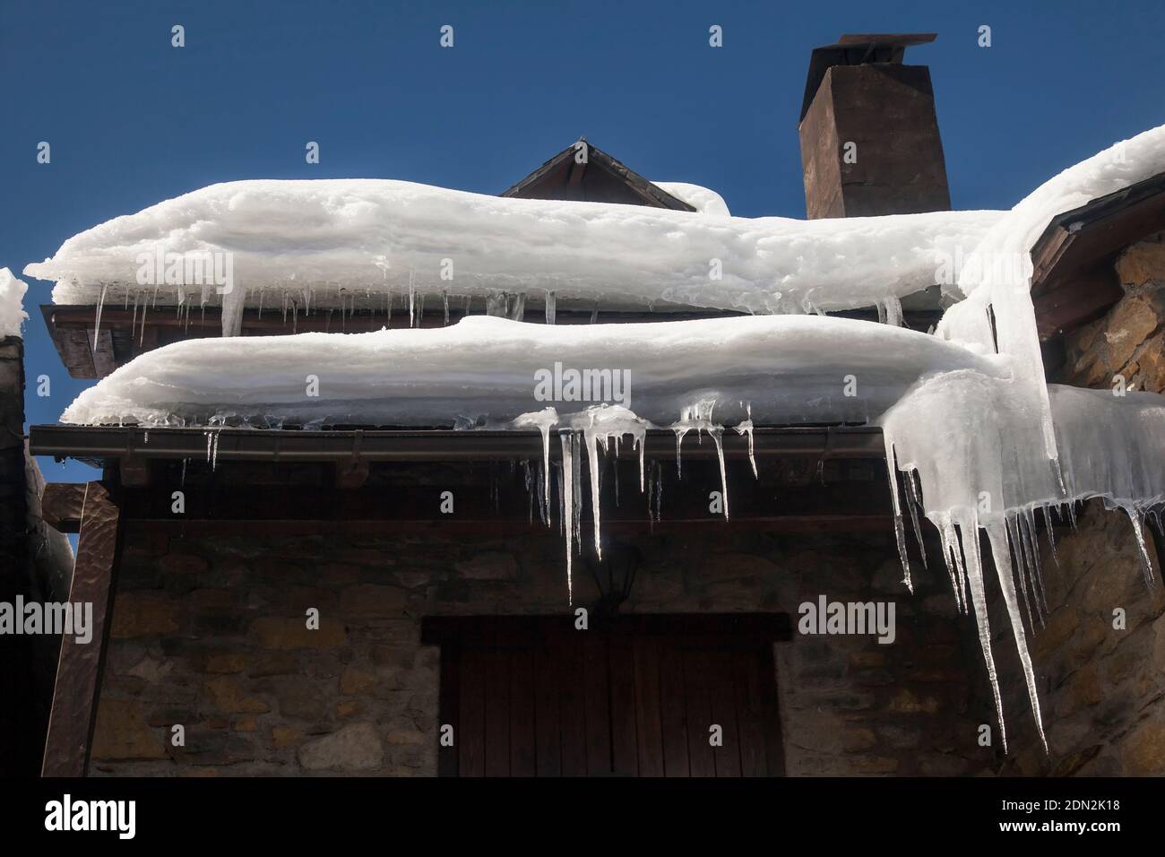 Horizontal low angle view of some icicles hanging from a house roof, Artíes, Vall d’Aran, Lleida, Catalonia, Spain Stock Photo