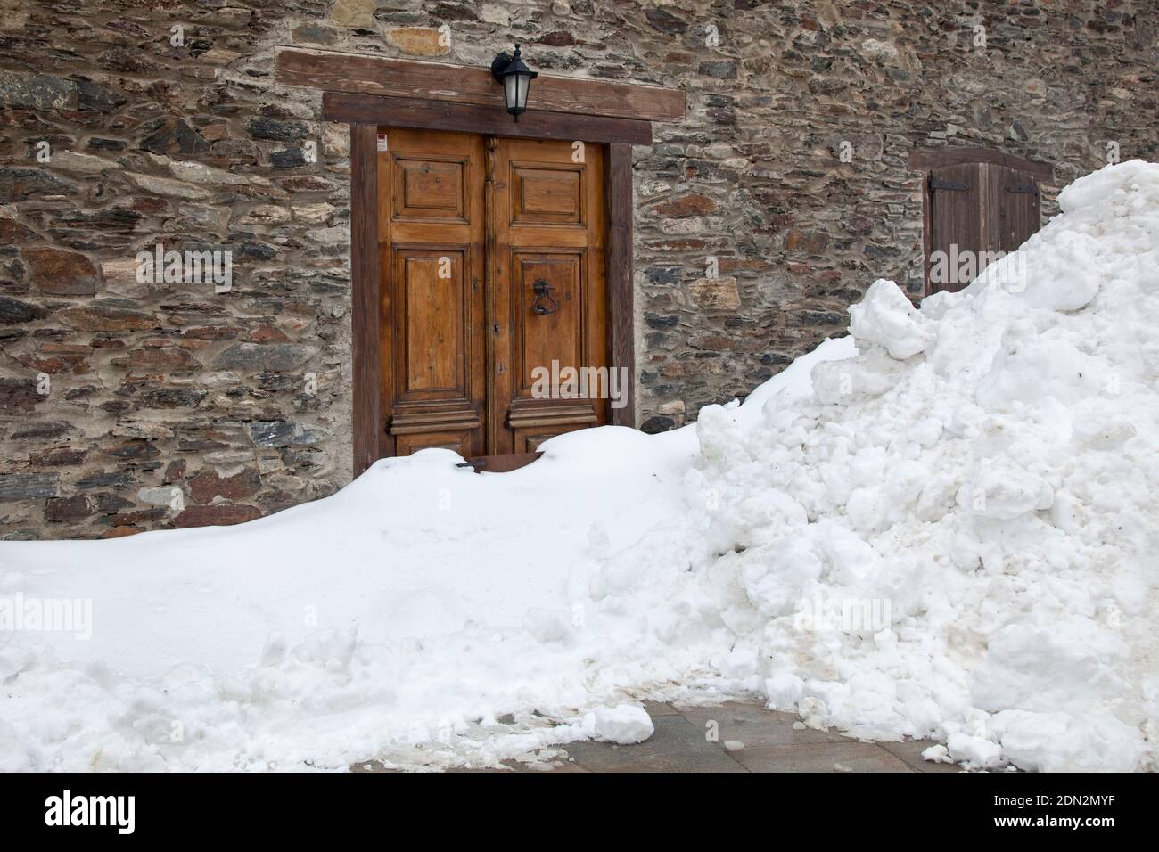 Horizontal shot of a huge pile of snow blocking the entrance of a mountain house, Vilamòs, Vall d’Aran, Lleida, Catalonia, Spain Stock Photo