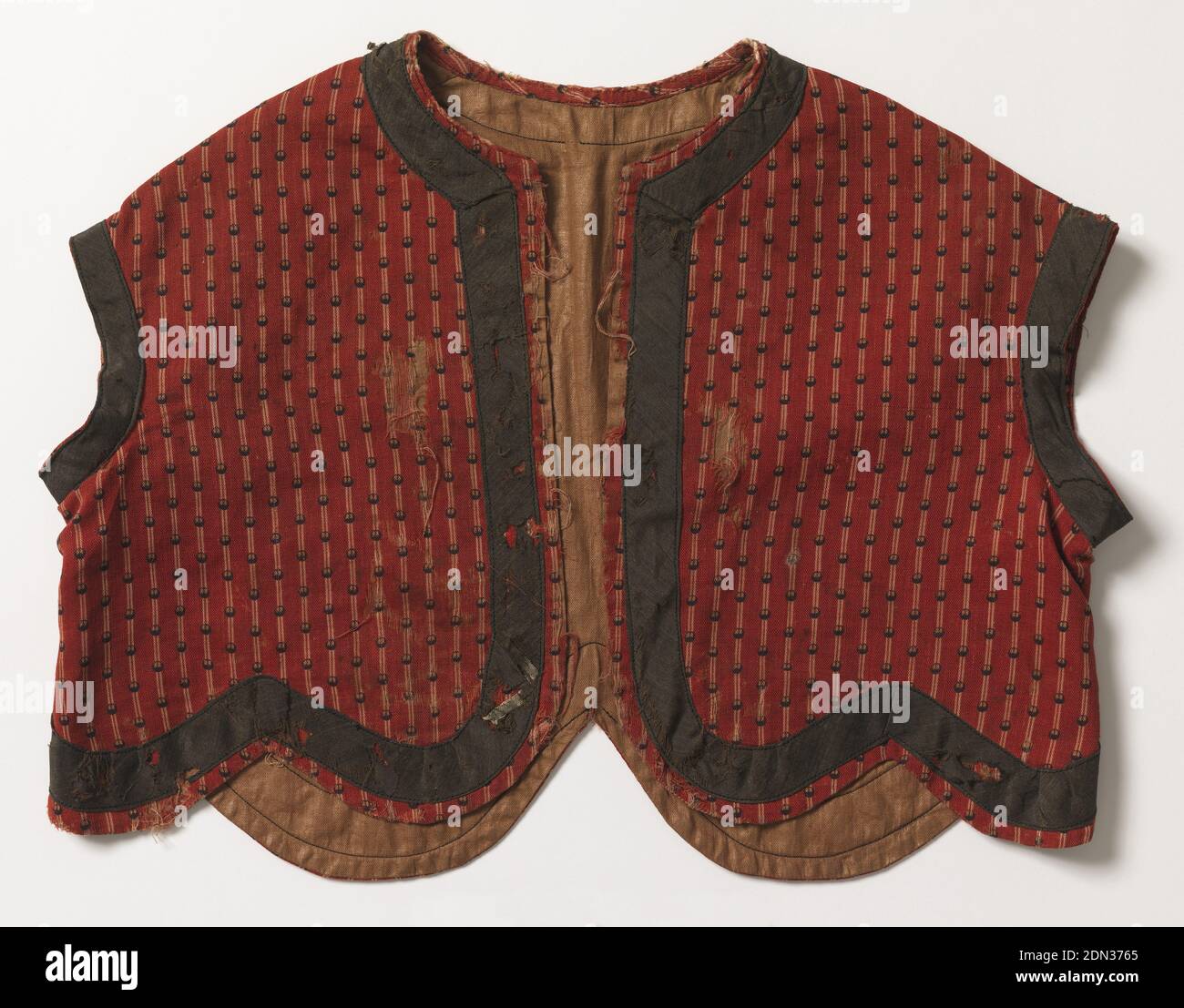 Vest, Medium: wool, glazed cotton Technique: printed, child's short jacket of red wool, striped in white and printed, over-stripe in small black dots. Roud neck, no sleeve, shaped, scalloped bottom. Trimmed with band of black wool around neck, arm hole and bottom, light brown glazed cotton lining. Machine sewn., ca. 1860, printed, dyed & painted textiles, Vest Stock Photo