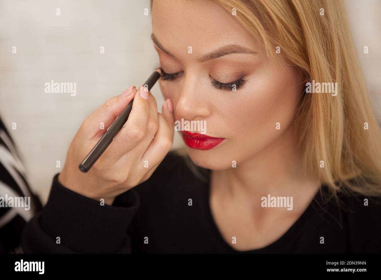Top view close up of a makeup artist using kajal on the eyes of a beautiful woman Stock Photo