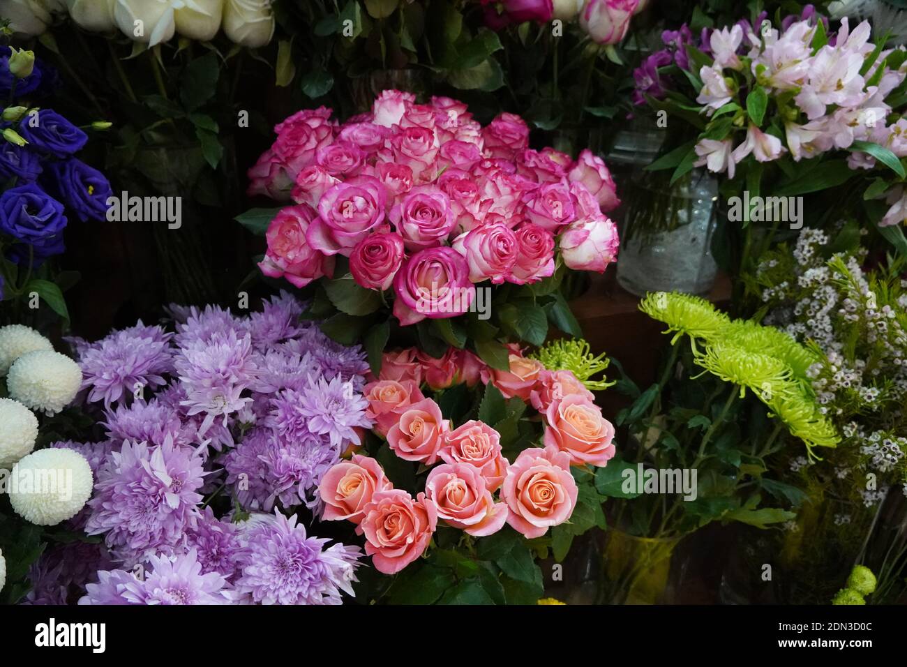 Bouquet of colorful roses and other different flowers at the entry to flower shop at farmers' market. Colorful peony, roses etc. Pots with flowers on Stock Photo