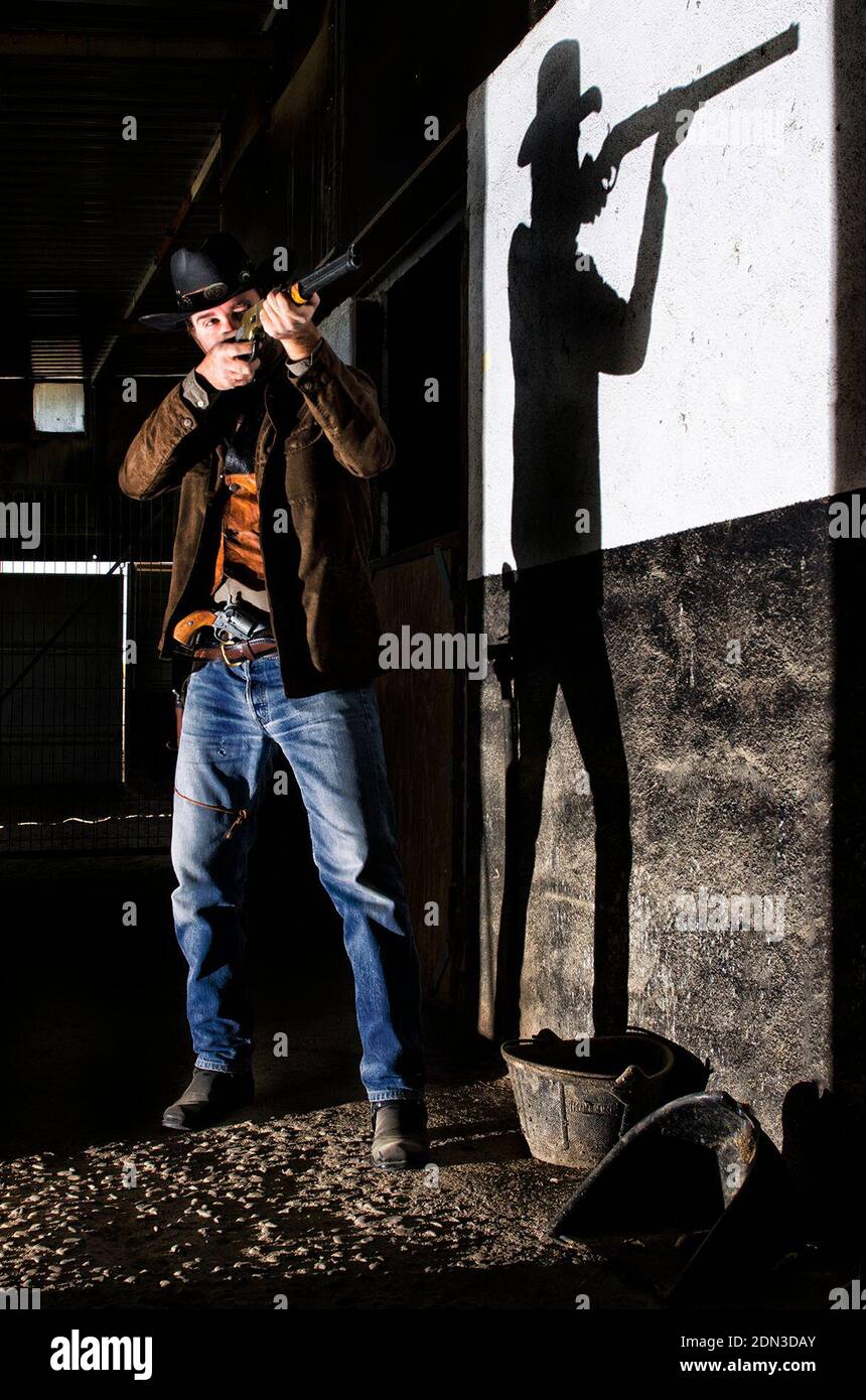 Man Shooting With Rifle By Wall Stock Photo
