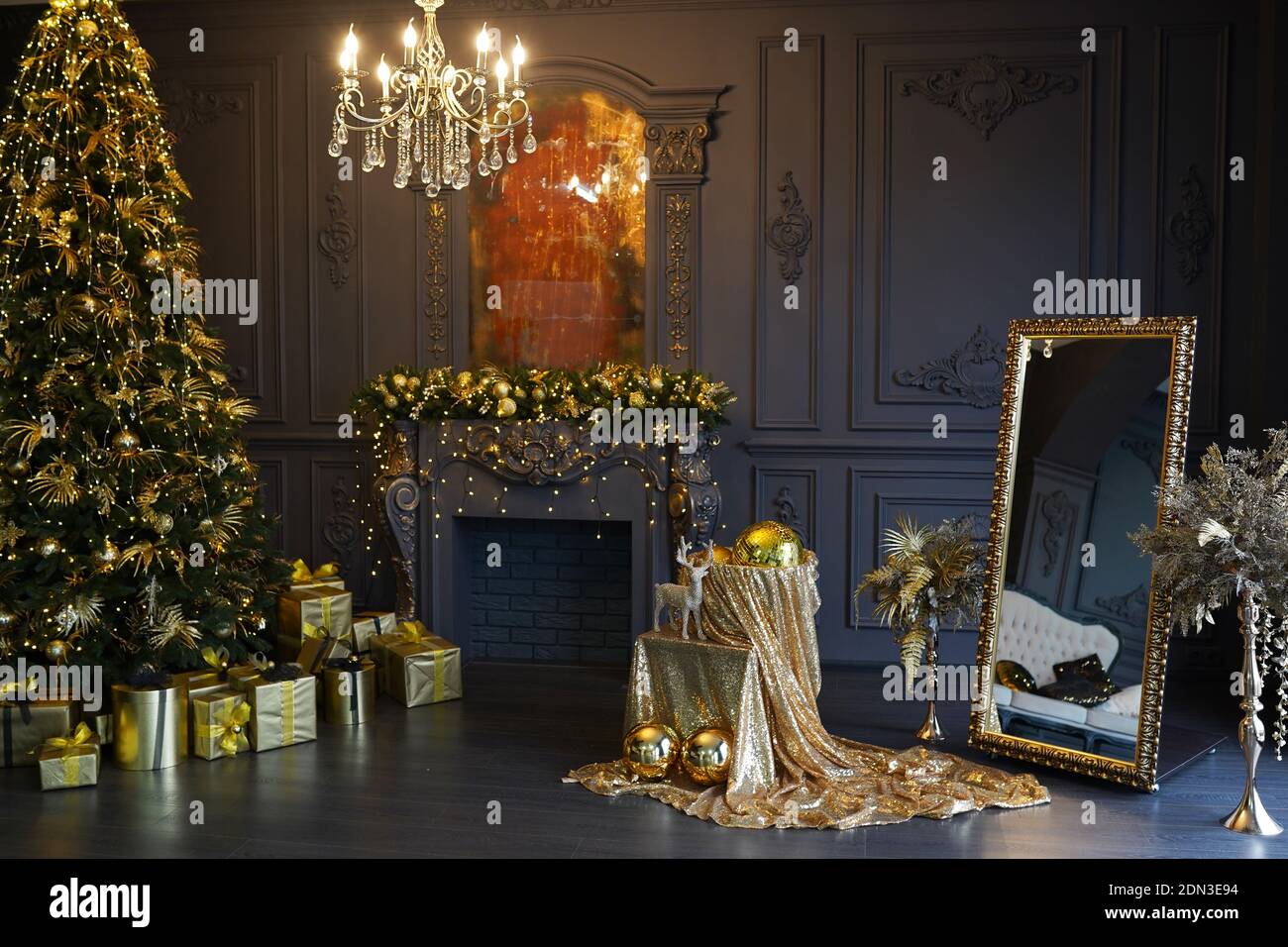 Snazzy christmas interior in living room, golden decorations , lights, christmas tree and heap of gifts, golden mirror and fireplace Stock Photo