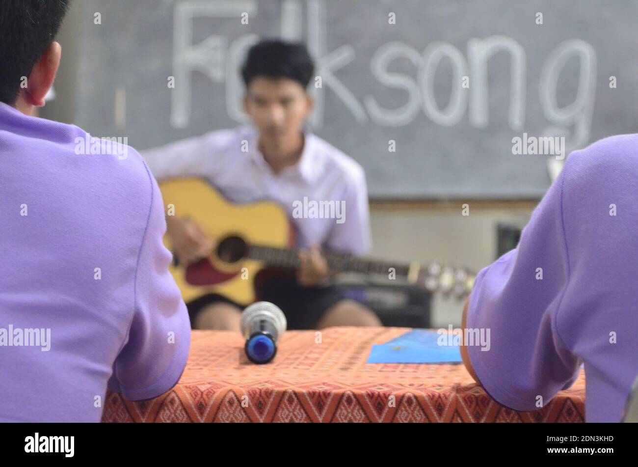 Rear View Of Judges Listening To Male Contestant Playing Guitar During Competition Stock Photo