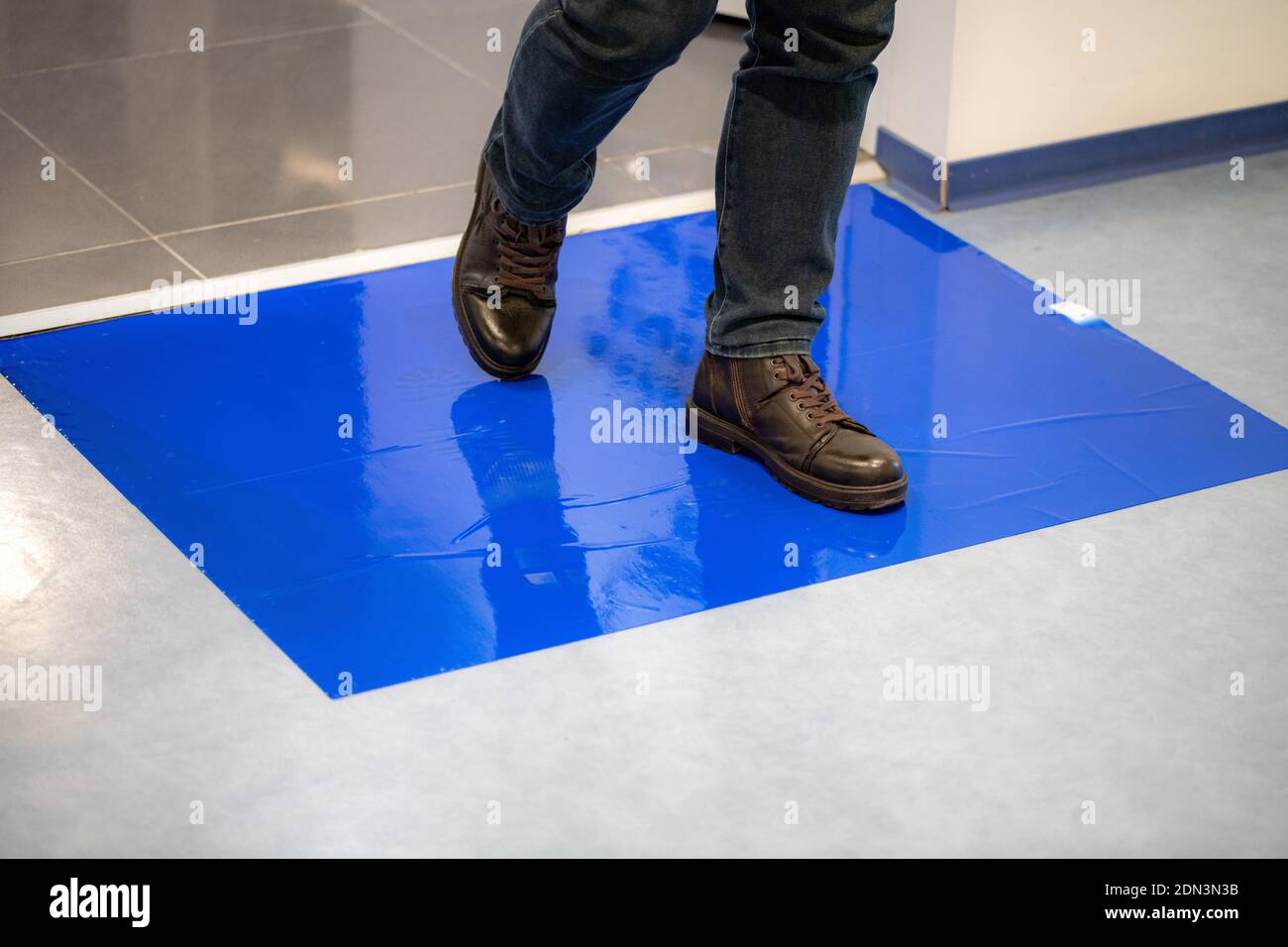 Man in brown shoes stepping on blue Adhesive Sticky Mats. Stock Photo