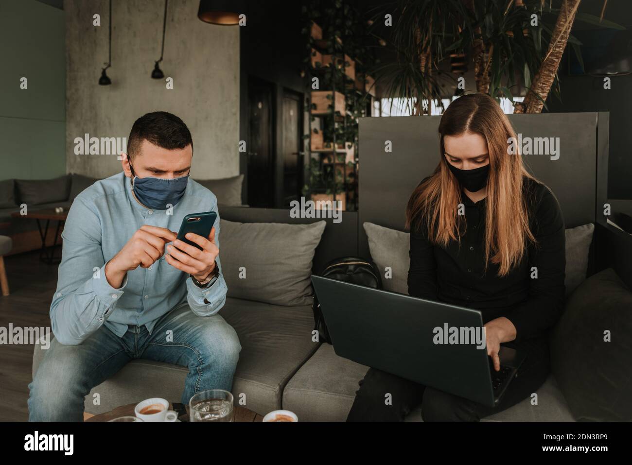 people with face mask using laptop and smartphone technology indoors Stock Photo