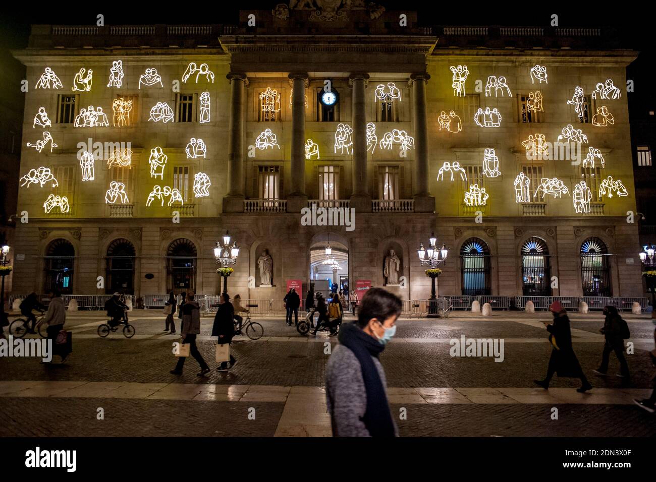 In Barcelona people wearing face masks walk past the facade of the city