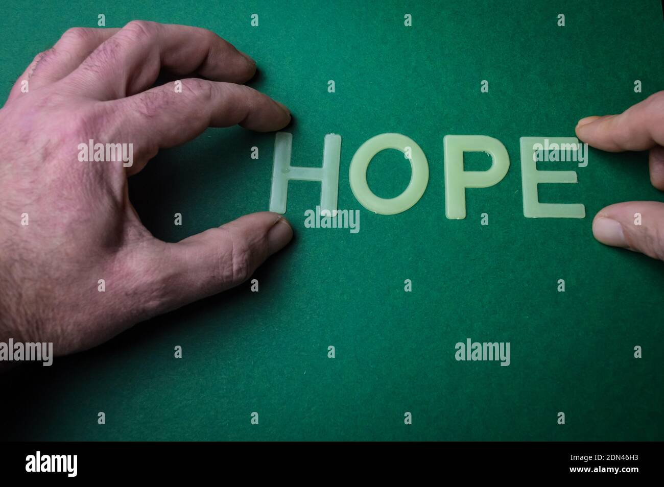 Human hand holding the word Hope written with plastic letters on green paper background, concept Stock Photo