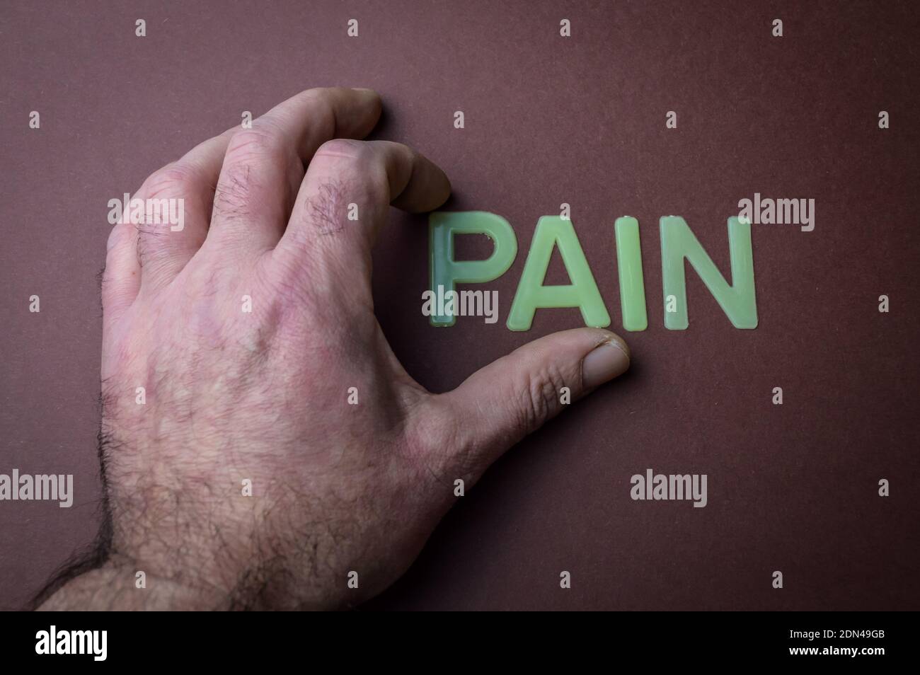 Human fingers holding the word Pain written with plastic letters on ...