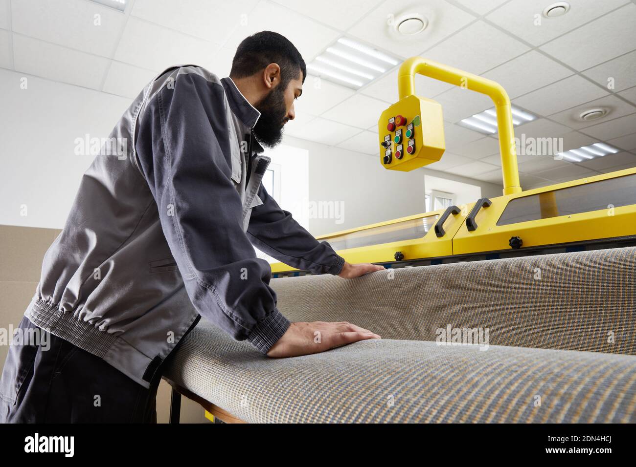 Man operating carpet automatic washing machine in professional laundry service Stock Photo