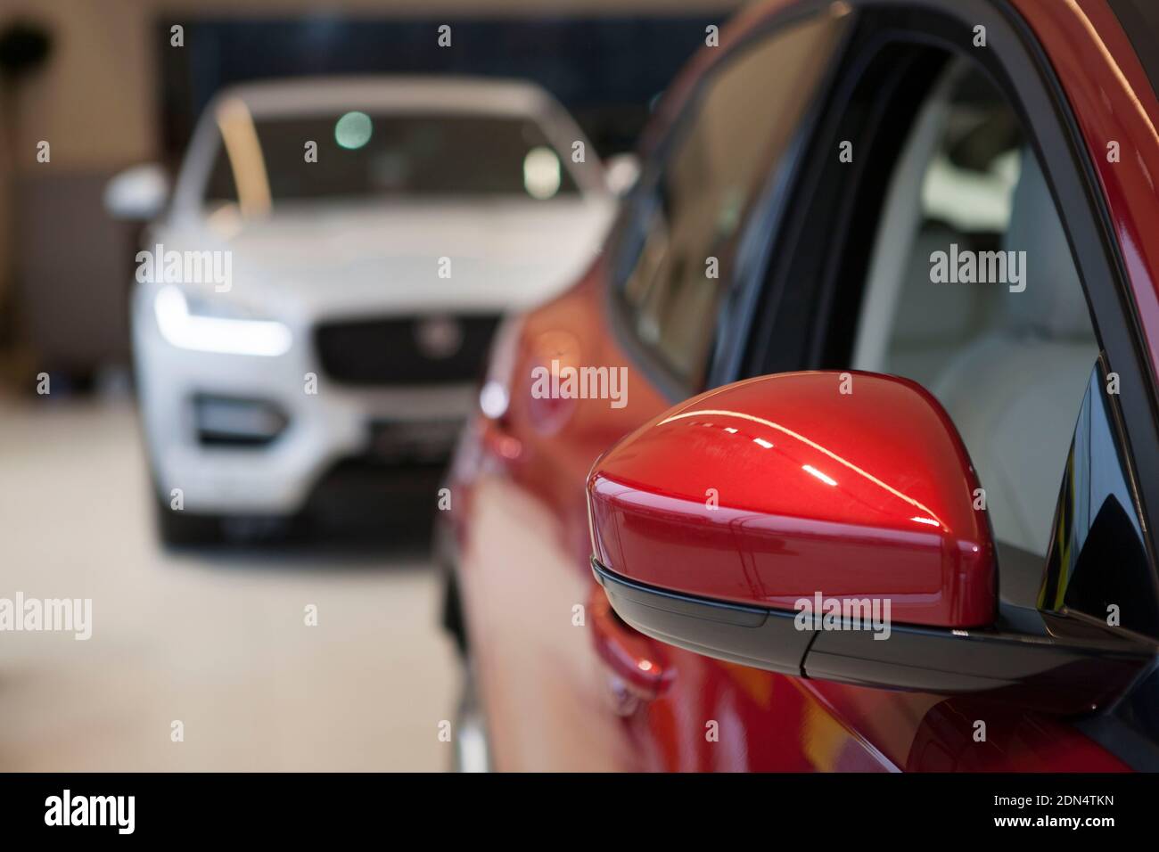 Selective focus on side mirror of a new red automobile at the dealership, copy space Stock Photo