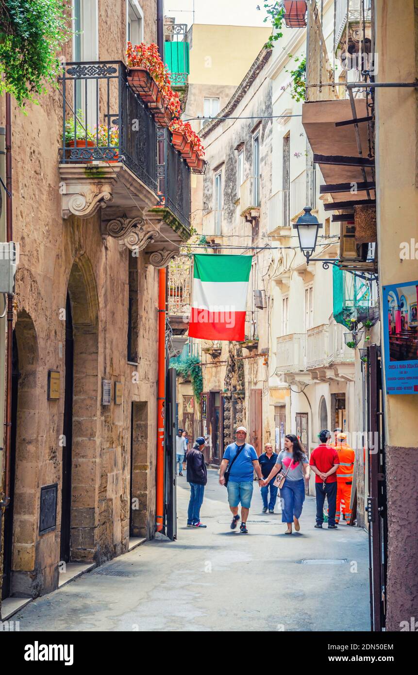 Taranto, Italy - May 7, 2018: typical italian narrow cobblestone street in Taranto historical city center with pare man and woman walking down, italia Stock Photo