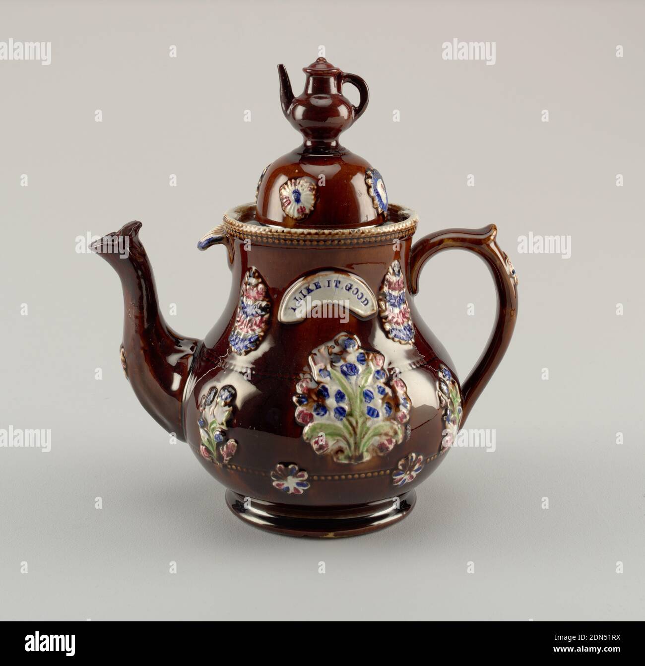 Barge Pot, 'I Like It Good', Glazed earthenware, A brown teapot and dome lid decorated with a flower pattern. On the side, a white arch says: 'I Like it Good'. The knob on the lid a miniature teapot., England, 18th–19th century, ceramics, Decorative Arts, Teapot and lid, Teapot and lid Stock Photo