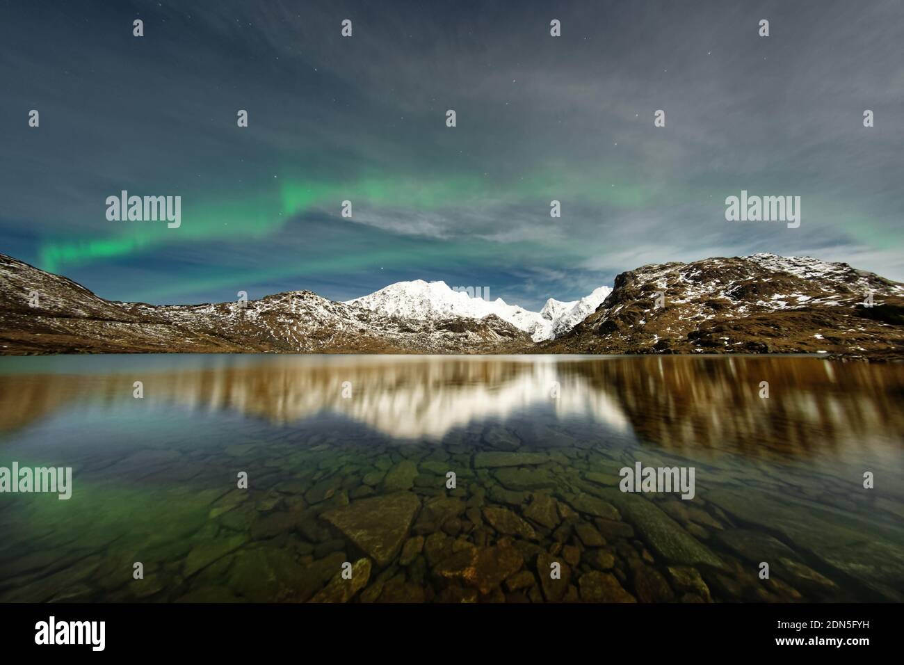 Northern lights over a mountain range reflected in a lake - Location: Norway, Lofoten Stock Photo