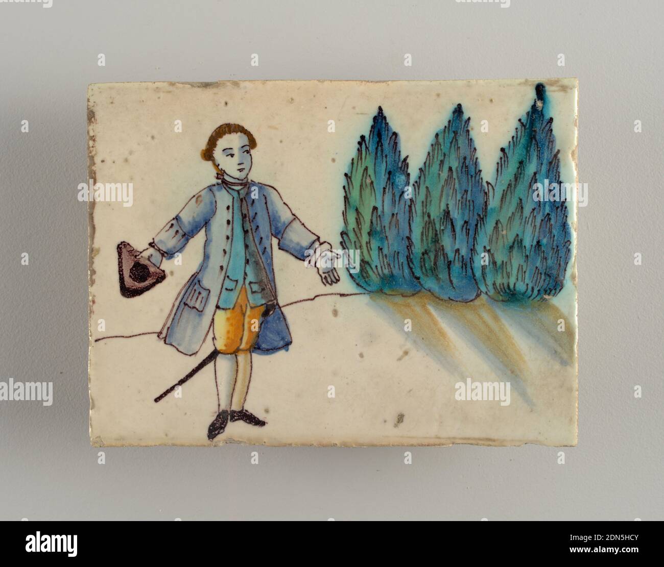 Tile, Lead glazed earthenware, Horizontal rectangle. Standing figure of peasant woman, head three-quarter to the left. Wears blue bodice, white scarf, white apron and full skirt, yellow shaded with brown. Palm tree at right., possibly Spain, late 18th century, tiles, Decorative Arts, Tile Stock Photo
