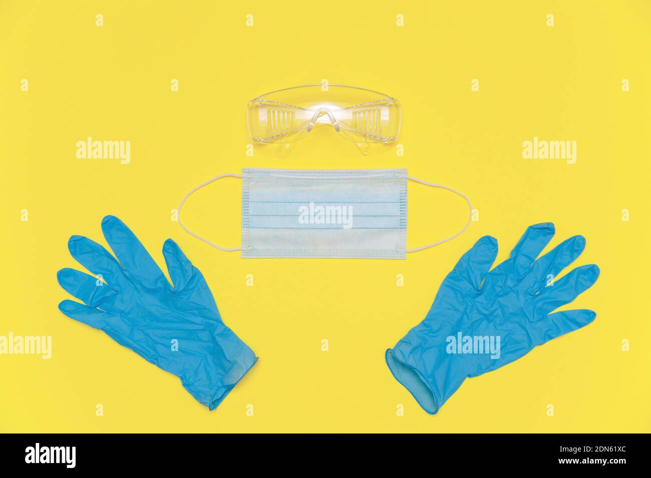 Coronavirus personal protective equipment. Medical nitrile gloves, protective glasses and mask on the yellow Illuminating background, color of the Stock Photo