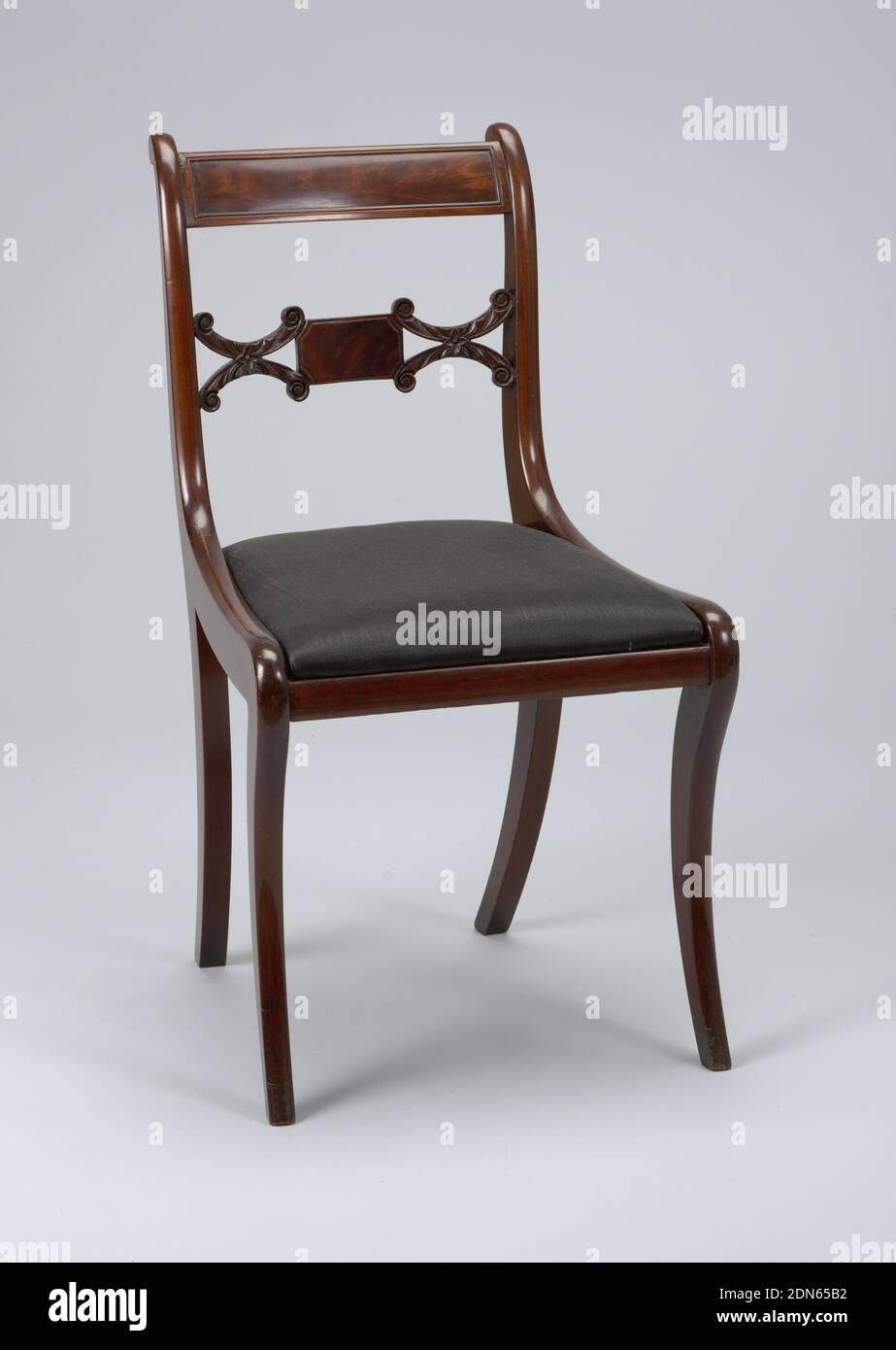 Side Chair, wood (mahogany), wood (poplar), horse hair (seat), Back legs flat-sided, front legs flat excepting rounded front face; legs curve outward towar bottom, and back legs incline toward each other at bottom. Corner posts of back terminate in a double curve with elementary volute form. Flat top rail bowed toward back, slightly arched, with a rectangular panel of inset veneer surrounded by beading. Splat horizontal, composed of small oblong faced with veneer, flanked on either side by horizontal coupled C-scrolls deeply carved with foliage, terminating in volutes. Stock Photo
