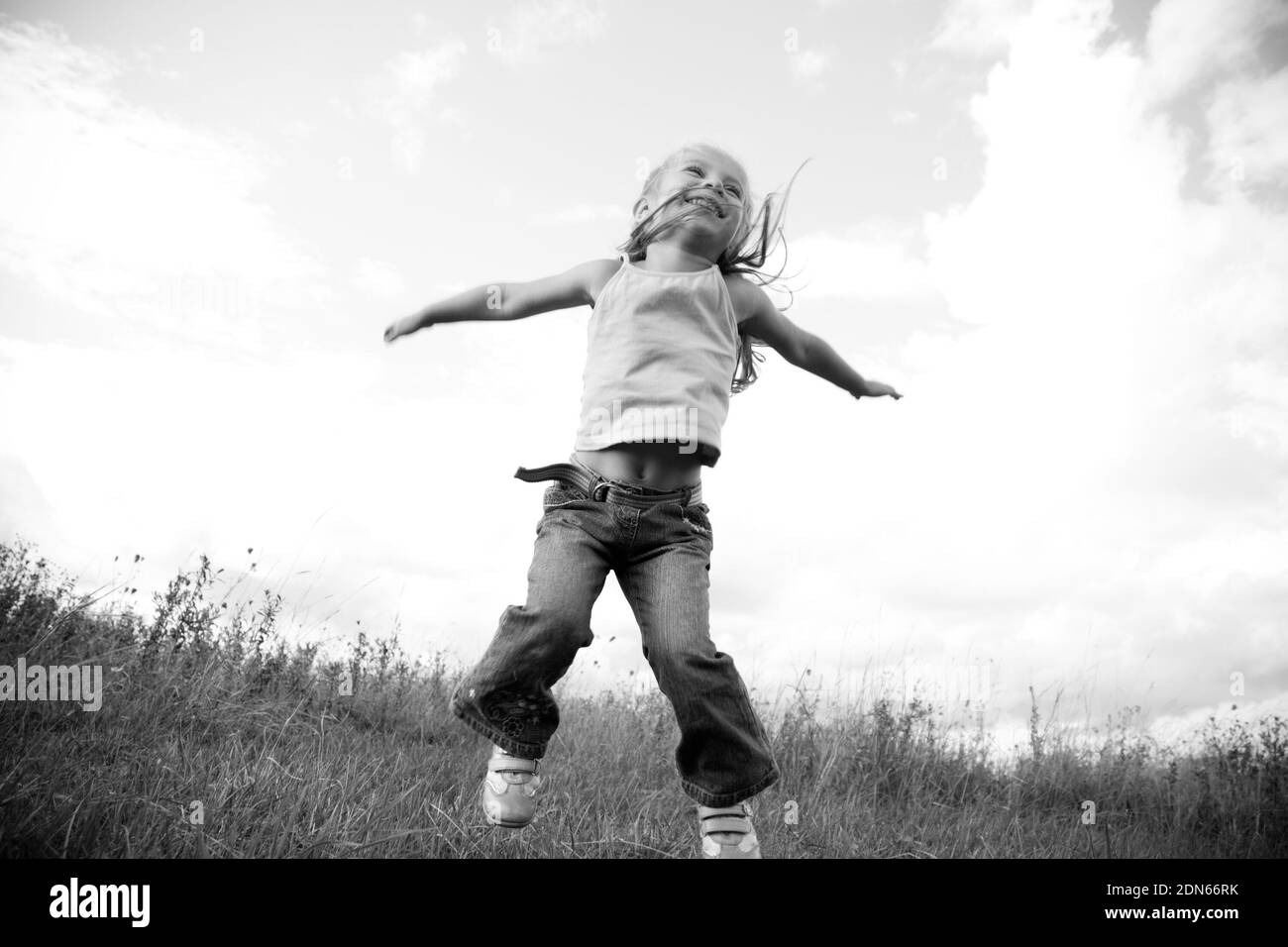 little girl jumping in the meadow Stock Photo
