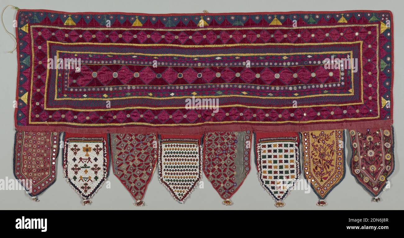 Hanging, Medium: silk, cotton, mirrored glass, glass beads Technique: surface, ladder, buttonhole and chain stitch embroidery on plain weave Label: surface, ladder, buttonhole and chain stitch silk embroidery on cotton ground with mirrored glass, glass beads, Hanging in the shape of a horizontal rectangle with eight tabs at the bottom. The rectangle is of blue cotton plain weave with embroidery in red and yellow silk in borders ornamented with discs of mirrored glass. Five tabs are of this type of embroidery and three are beadwork., India, 19th century, embroidery & stitching, Hanging Stock Photo