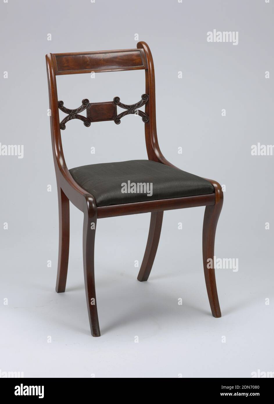 Chair, wood (mahogany), wood (poplar), horse hair, Back legs flat sided, front legs flat excepting rounded front face; legs curve outward toward bottom, and back legs incline toward eachother at bottom. Corner posts of back in a double curve terminating at top in on elemenatary volute form. Flat top rail bowed toward back, slightly arched, with a rectangular panel of inset veneer surrounded by beading. Splat horizontal, composed of small oblong faced with veneer, flanked oneither side by horizontal coupled C-scrolls deeply carved with foliage, terminating in volutes. Stock Photo