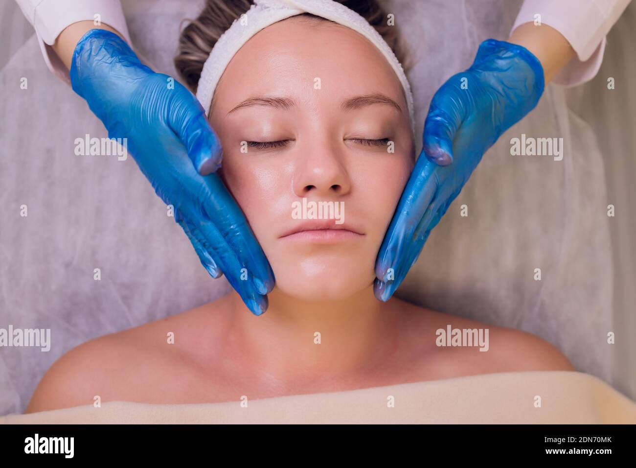 Top view of beautiful young woman getting face skin treatment