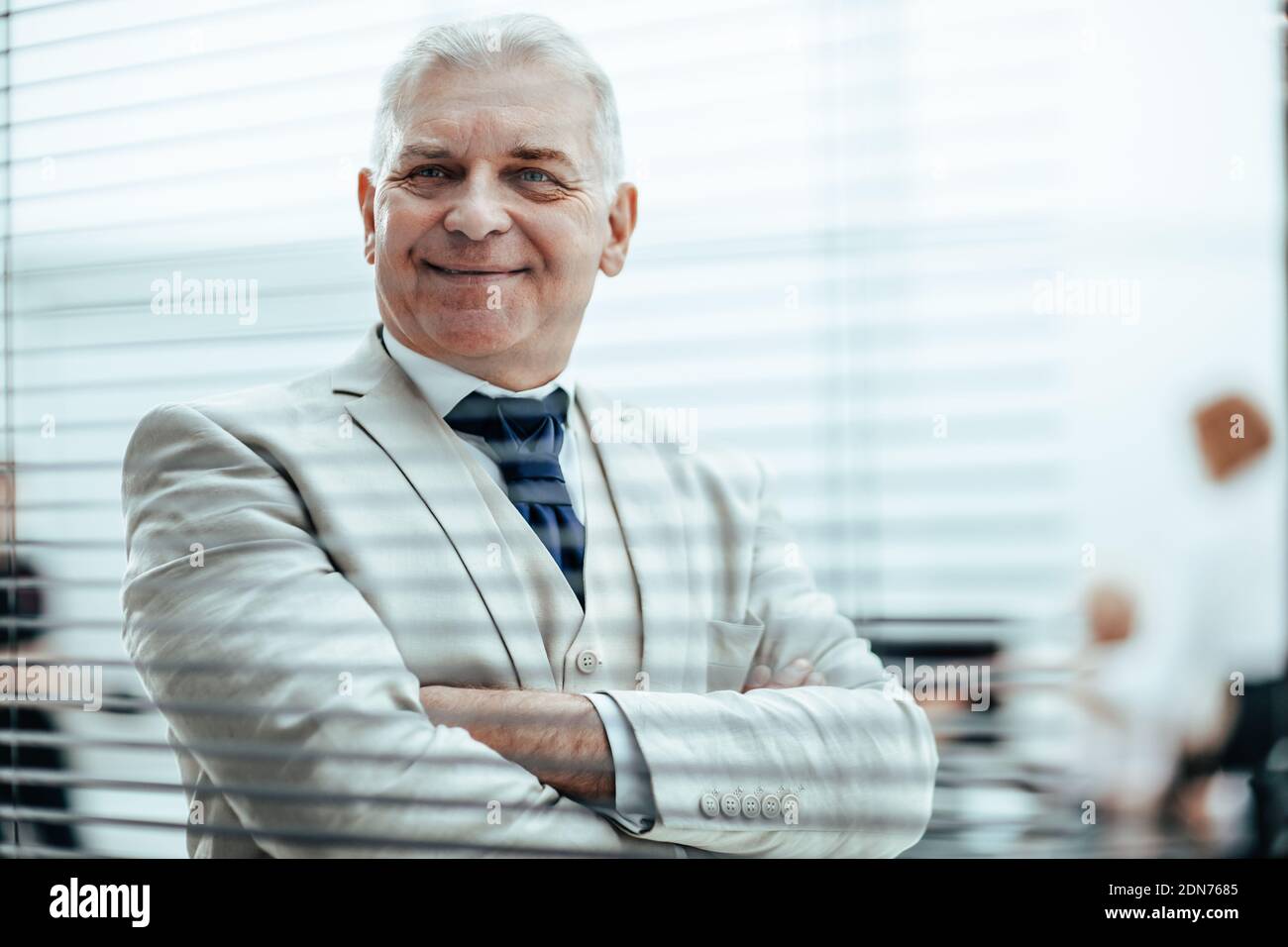 smiling Mature businessman looking through office window blinds. Stock Photo