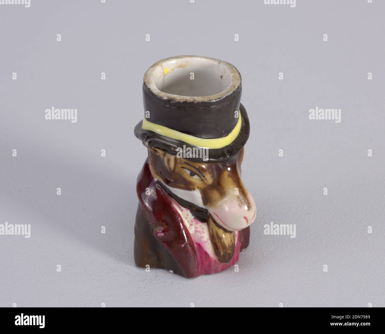 matchsafe, Porcelain, Figure of donkey wearing top hat with yellow band. Figure also wears maroon coat with magenta waistcoat and white shirt with magenta dots., probably England, late 19th century, containers, Decorative Arts, matchsafe Stock Photo