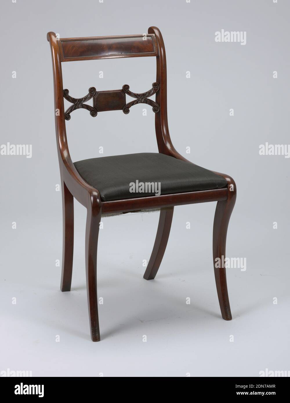 Side chair and slip seat, mahogany,poplar,horse hair, Back legs flat-sided, front legs flat excepting rounded front face; legs curve outward toward bottom, and back legs incline toward each other at bottom. The chair's back corner posts terminate in a volute-like form at the top of the chair. The chair's top rail, slightly arched, is bowed towards the back. A rectangular panel of inset veneer is surrounded by beading. The chair's splat is horizontal, composed of a small oblong-shaped rectangle faced with veneer, flanked on either side by horizontal coupled C-scrolls covered with foliage. Stock Photo
