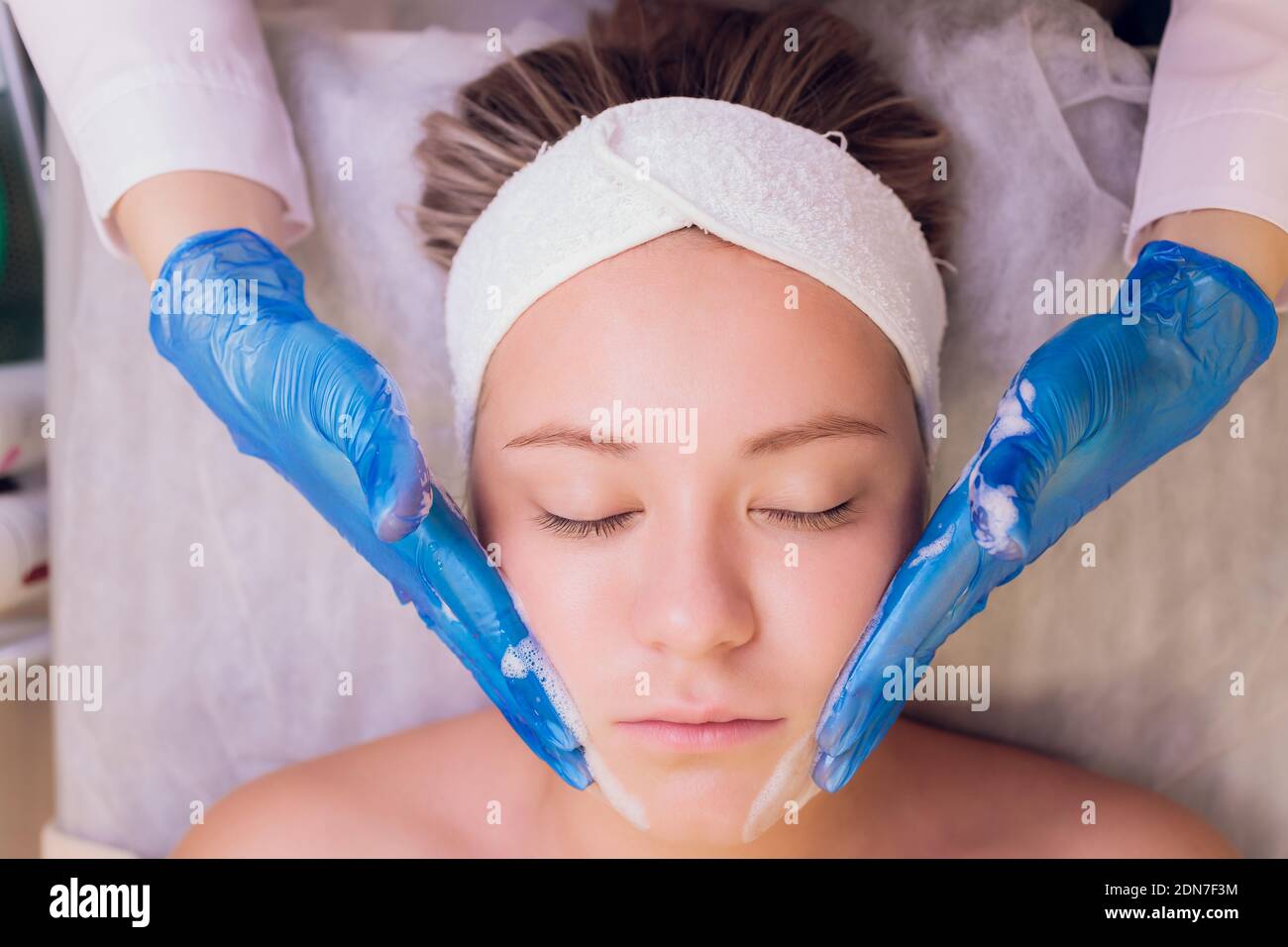 Top view of beautiful young woman getting face skin treatment