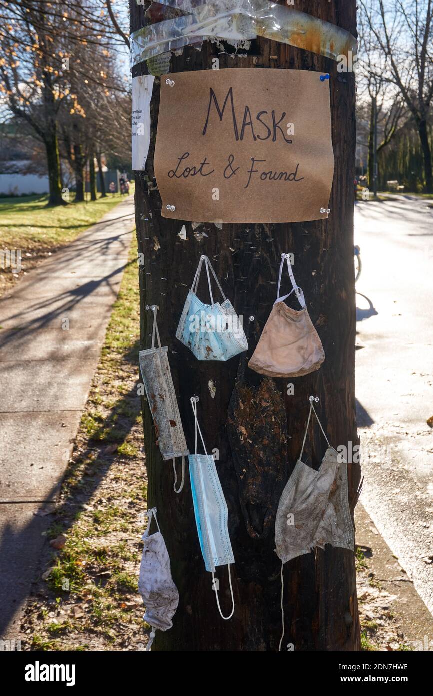 Discaded COVID-19 protective masks and a mask lost and found sign pinned to a utility pole in Vancouver, BC, Canada Stock Photo