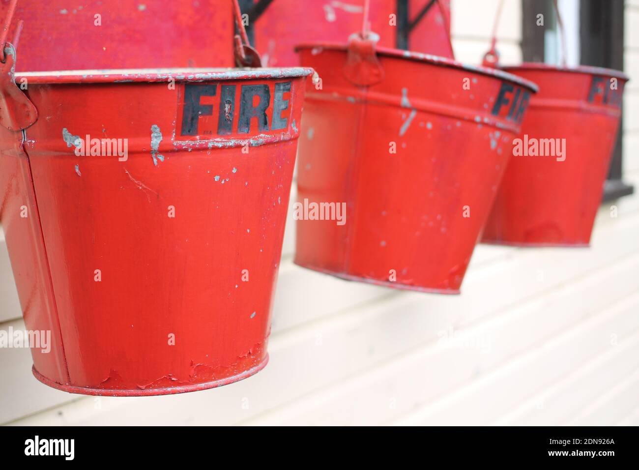 Close-up Of Red Metal Buckets With Fire Text Hanging Against Wall Stock Photo